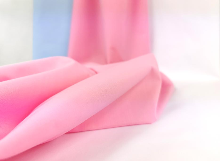 Zdjęcie przedstawiające różową tkaninę Elanobawełnę Venetus na tle materiałów w kolorze błękitnym i białym