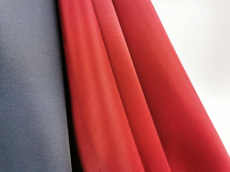 Zdjęcie przedstawiajace tkaninę poliestrowo-bawełnianą, Elanobawełnę Biver w kolorze grafitowym oraz czerwieni wiśniowej w przybliżeniu na strukturę materiału