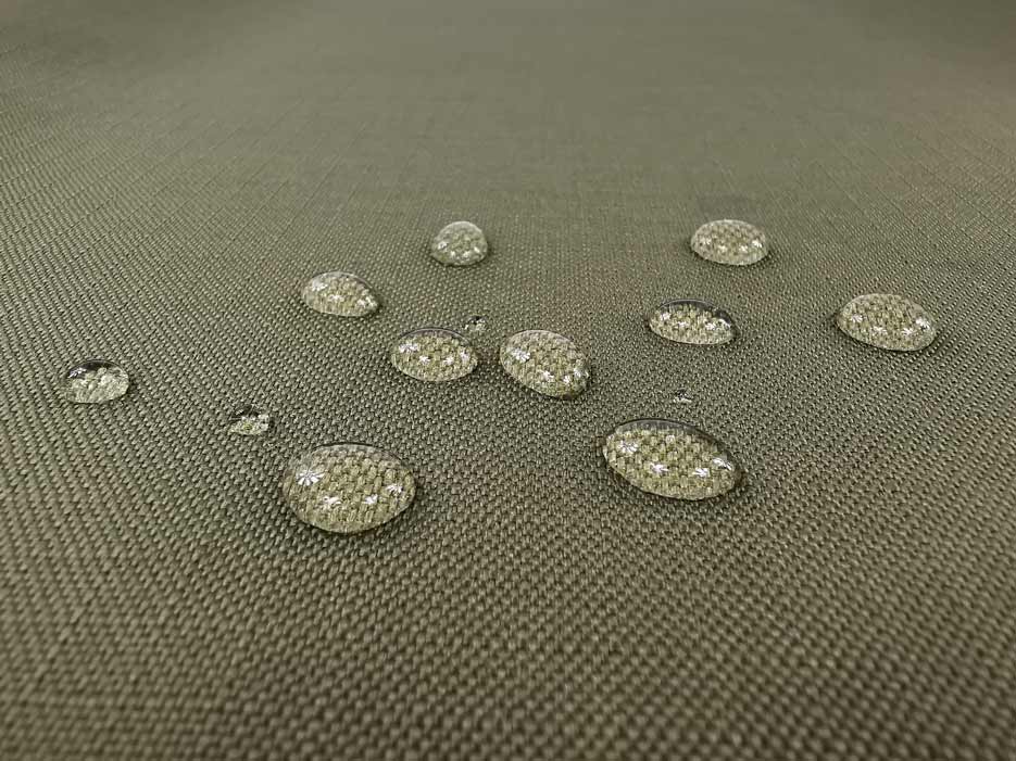 Zdjęcie przedstawiające przybliżenie na zieloną tkaninę wodoodporną Ripstop z kroplami wody na powierzchni materiału