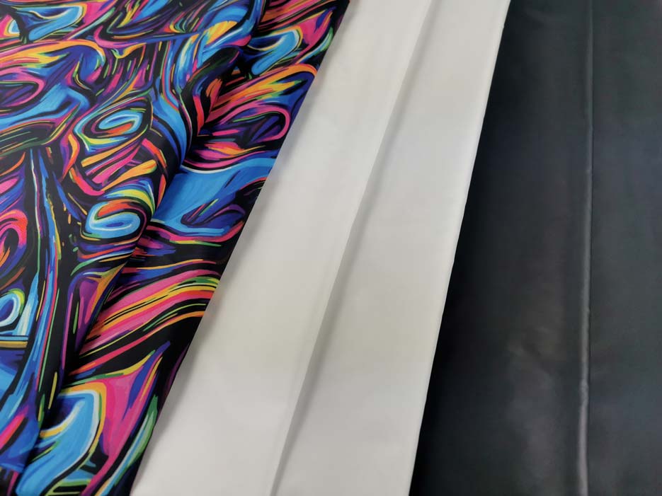Zdjęcie prezentujące tkaninę wodoodporną Ortalion Pumi w wersji z kolorowym nadrukiem, bieli i czerni