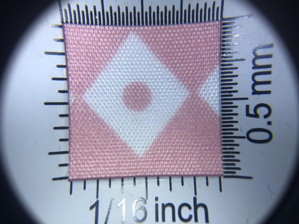 Zdjęcie przedstawia art. BS616, (100% poliester, gramatura 70 g/m2, szerokość 165 cm) w kolorze różowym (nr. 3227), we wzorze 702, w przybliżeniu, pod lupą, wygląd struktury tkaniny.
