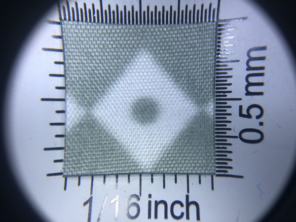 Zdjęcie przedstawia art. BS616, (100% poliester, gramatura 70 g/m2, szerokość 165 cm) w kolorze szarym (nr. 4120), we wzorze 702, w przybliżeniu, pod lupą, wygląd struktury tkaniny.