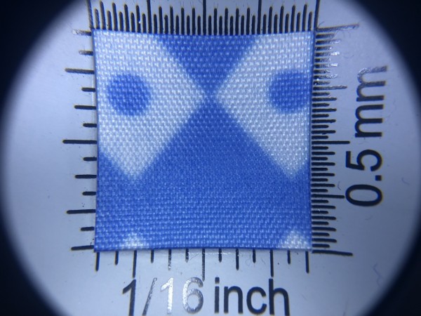 Zdjęcie przedstawia art. BS616, (100% poliester, gramatura 70 g/m2, szerokość 165 cm) w kolorze niebieskim (nr. 5031), we wzorze 702, w przybliżeniu, pod lupą, wygląd struktury tkaniny.