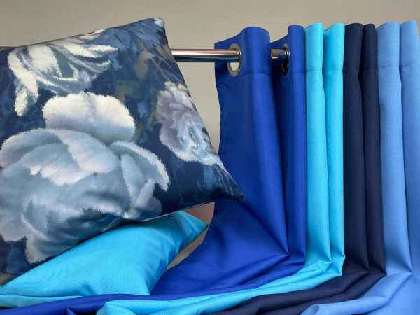 Zdjęcie prezentujące niebieskie tkaniny poliestrowe Panama Stretch (strecz) w formie gotowych wyrobów - zasłon i poduszki
