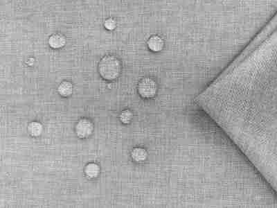 Zdjęcie prezentujące tkaninę obiciową wodoodporną ze wzorem melanżowym w odcieniach jasnej szarości z kroplami wody na powierzchni materiału