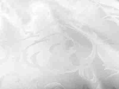Zdjęcie przedstawiajace przybliżenie na białą tkaninę obrusową żakardową ze wzorem ornamentowym