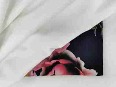 Zdjęcie prezentujące białą tkaninę wodoodporną Softshell SL32 ułożoną na materiale z nadrukowanym wzorem w kwiaty 