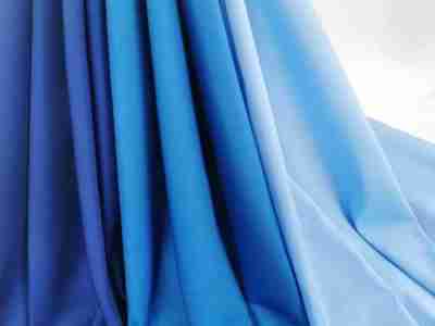 Zdjęcie prezentujące Elanobawełnę Radus, tkaninę na odzież medyczną  w trzech odcieniach koloru niebieskiego- atramentowym, lazurowym oraz jasnym błękicie