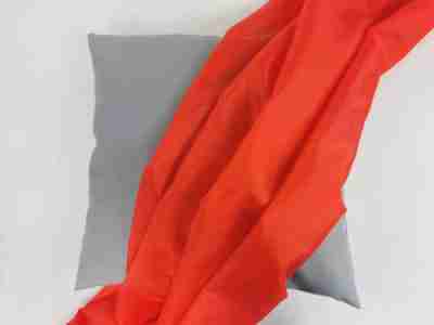 Zdjęcie prezentujące czerwoną tkaninę podszewkową poliestrową na tle poduszki w kolorze szarym