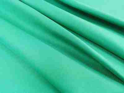 Zdjęcie przedstawiające tkaninę poliestrową  o splocie diagonalnym w kolorze jasnej zieleni w przybliżeniu na strukturę materiału