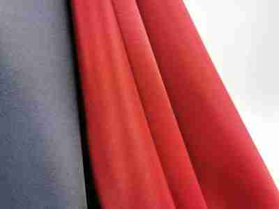 Zdjęcie przedstawiajace tkaninę poliestrowo-bawełnianą, Elanobawełnę Biver w kolorze grafitowym oraz czerwieni wiśniowej w przybliżeniu na strukturę materiału