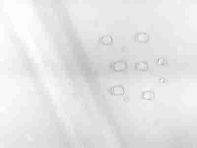 Zdjęcie przedstawiające tkaninę żakardowa obrusową, plamoodporną w kolorze białym z kroplami wody na powierzchni materiału