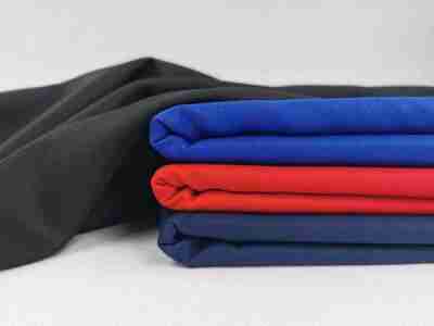 Zdjęcie przedstawiające tkaninę poliestrową o splocie diagonalnym w kolorze czarnym, niebieskim, czerwonym oraz granatowym
