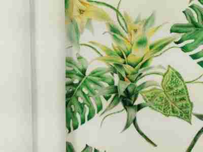 Zdjęcie przedstawiające przybliżenie na tkaninę żorżeta-materiał na sukienki i zasłony- w kolorze białym oraz z nadrukiem w tropikalne rośliny w odcieniach zieleni