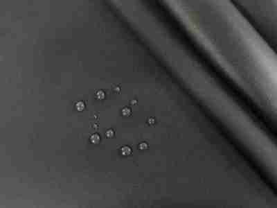 Zdjęcie przedstawiające wierzchnią i spodnią stronę tkaniny wodoodpornej typu oxford w kolorze czarnym z widocznymi kroplami wody na powierzchni materiału
