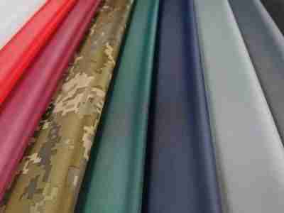 Zdjęcie przedstawiające tkaninę poliestrową wodoodporną Ortalion S40 w przykładowej kolorystyce, bieli, odcieniach czerwieni, wzorze moro, zieleni, granacie oraz odcieniach szarości